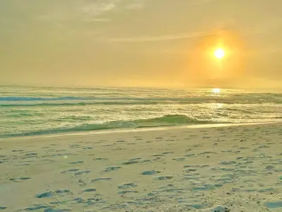 a beach with the sun setting over the ocean at A Wave From It All in Laguna Beach Large Patio Sleeps 4 Dog Ok in Panama City Beach