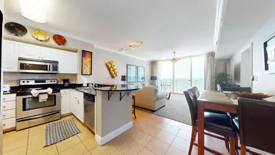 a kitchen and living room with a table and a couch at Tidewater 0509 in Panama City Beach