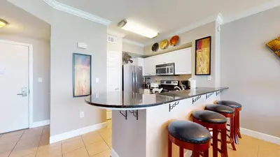 a kitchen with a counter with bar stools at Tidewater 0509 in Panama City Beach