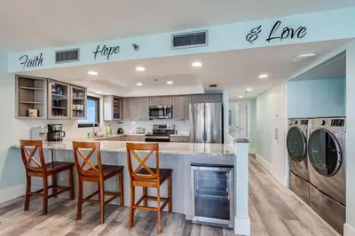 a kitchen with a counter with three chairs at a bar at Watercrest 1510 - Timeless Memories Stunning views in Panama City Beach