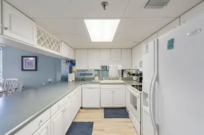 a kitchen with white cabinets and a refrigerator at Watercrest 1509 - Sleeps 8 Amazing sunsets in Panama City Beach
