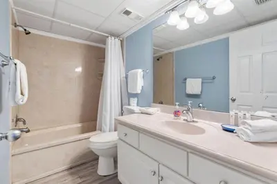 a bathroom with a sink and a toilet and a mirror at Watercrest 1509 - Sleeps 8 Amazing sunsets in Panama City Beach
