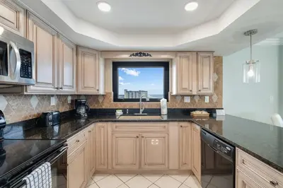 a kitchen with wooden cabinets and a window at Watercrest 1201 - Swell Life - Sleeps 8 2 BR 2 BA in Panama City Beach