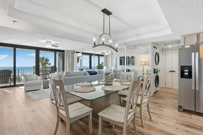a dining room and living room with a table and chairs at Watercrest 207 3 BR 3 BA with 2 Beachfront Masters in Panama City Beach