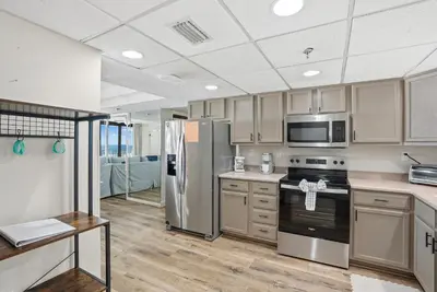 a kitchen with stainless steel appliances and wooden floors at Watercrest 207 3 BR 3 BA with 2 Beachfront Masters in Panama City Beach
