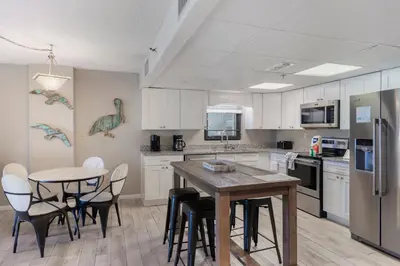 a kitchen with white cabinets and a table and chairs at Watercrest 210- Sleeps 12 - Thomas Drive Retreat in Panama City Beach