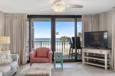 a living room with a television and a balcony with the ocean at Watercrest 210- Sleeps 12 - Thomas Drive Retreat in Panama City Beach