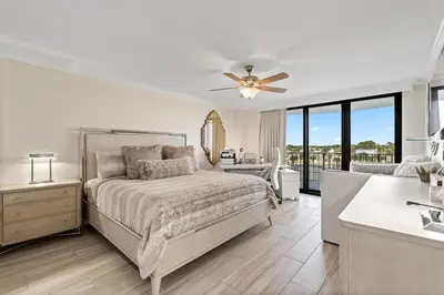 a white bedroom with a bed and a bathroom at Watercrest 401 Amazing wrap around balcony in Panama City Beach