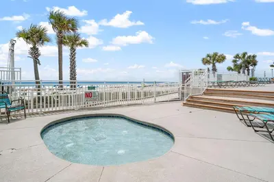 a small swimming pool next to a beach with palm trees at Watercrest 401 Amazing wrap around balcony in Panama City Beach
