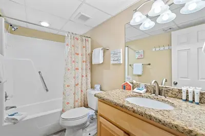 a bathroom with a sink and a toilet and a mirror at Watercrest 209 White-Sands Getaway - Sleeps 8 in Panama City Beach