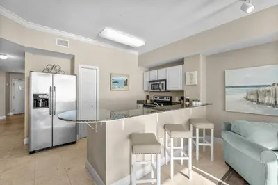 a kitchen and living room with a refrigerator and a counter at Family-Friendly Gulf-Front Condo w/Beach Access in Panama City Beach