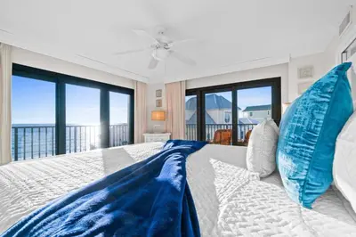 a bedroom with a large bed with blue pillows at Commodore 410 in Panama City Beach