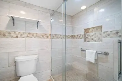 a bathroom with a toilet and a glass shower at Commodore 410 in Panama City Beach