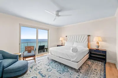 a bedroom with a bed and a blue chair at Grande Surf Club 11E in Panama City Beach