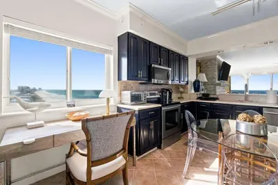 a kitchen with black cabinets and a glass table at Grande Surf Club 11E in Panama City Beach