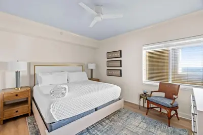 a bedroom with a bed and a chair and a window at Grande Surf Club 11E in Panama City Beach