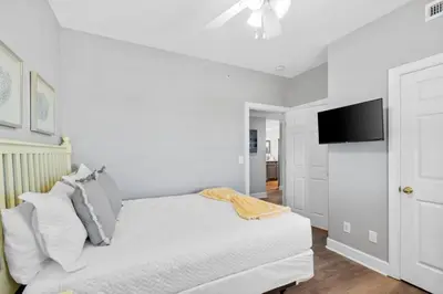 a white bedroom with a bed and a flat screen tv at Family-Friendly 4BR Beachfront Retreat w/ Indoor & Outdoor Pools in Panama City Beach
