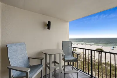 a balcony with three chairs and a table and the beach at Sunbird 407E - Pearl Gulf Getaway - Sleeps 4 in Panama City Beach