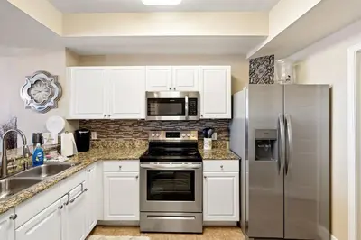 a kitchen with white cabinets and a stainless steel refrigerator at Tidewater 2405 - Tidewater Peak Sleeps 6 - 2Br 2Ba in Panama City Beach