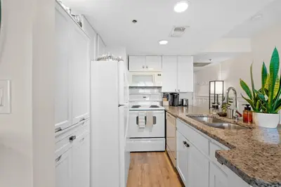 a white kitchen with white cabinets and a sink at Sunbird 110W 1 BR 1 BA Located right next to pool in Panama City Beach