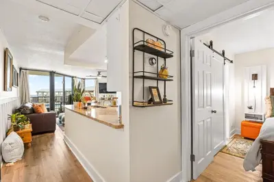 a kitchen and living room with white walls and a hallway at Sunbird 110W 1 BR 1 BA Located right next to pool in Panama City Beach