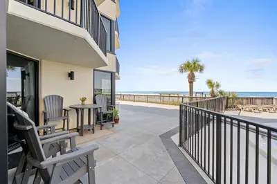a balcony with chairs and a table overlooking the beach at Sunbird 110W 1 BR 1 BA Located right next to pool in Panama City Beach