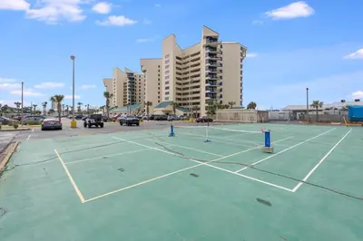 a parking lot with two tennis courts in front of a building at Sunbird 110W 1 BR 1 BA Located right next to pool in Panama City Beach