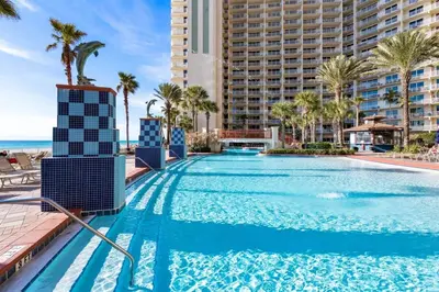 a swimming pool at the resort with palm trees and the ocean at Shores of Panama 926 - Shore-Gulf Peak- 2 BR 2 BA in Panama City Beach