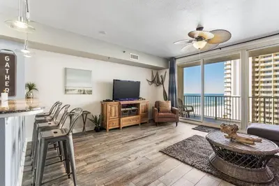 a living room with a television and a balcony at Shores of Panama 926 - Shore-Gulf Peak- 2 BR 2 BA in Panama City Beach