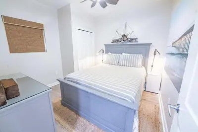 a white bedroom with a blue bed and a window at Sterling Reef 503 - Pierview Oasis - Sleeps 6 in Panama City Beach
