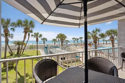 a table with an umbrella on a balcony overlooking the beach at Summit 225 - Low floor beachfront - Sleeps 5 in Panama City Beach