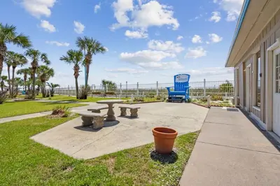 a patio with a picnic table and a blue chair at Summit 225 - Low floor beachfront - Sleeps 5 in Panama City Beach