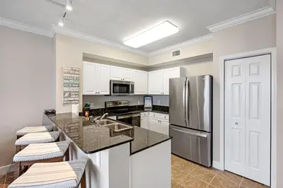 a kitchen with white cabinets and a stainless steel refrigerator at Tidewater 2411 - Tidewater Retreat - Sleeps 8 in Panama City Beach