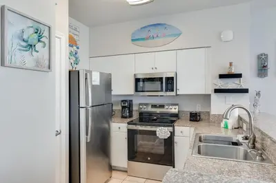 a kitchen with white cabinets and a stainless steel refrigerator at Shores of Panama 1403 - 3 BR 2 Ba Newly Renovated in Panama City Beach