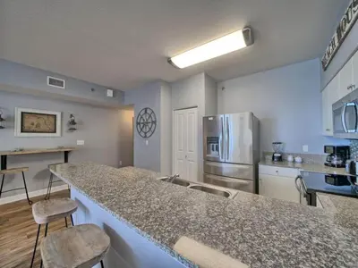 a kitchen with a counter top and a refrigerator at Shores of Panama 1307, Two Masters! in Panama City Beach
