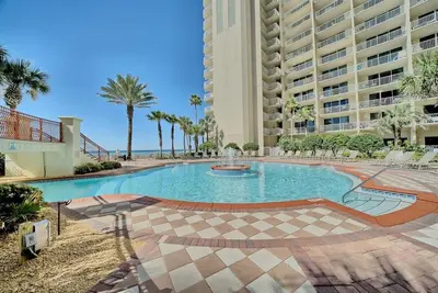 a swimming pool with palm trees and a large building at Shores of Panama 1307, Two Masters! in Panama City Beach