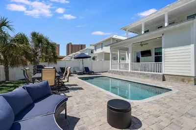 a swimming pool with a blue couch and a house at 221 Sands Street - 4 BR with Private pool in Panama City Beach