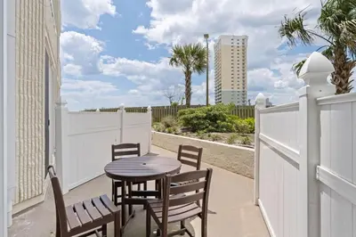a patio with a table and chairs and a fence at Top of the Gulf 120 - Shore-side Bungalow Sleeps 4 in Panama City Beach