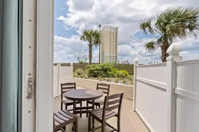 a patio with a table and chairs and a fence at Top of the Gulf 120 - Shore-side Bungalow Sleeps 4 in Panama City Beach