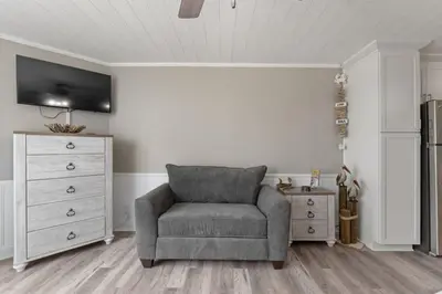 a living room with a chair and a dresser at Top of the Gulf 120 - Shore-side Bungalow Sleeps 4 in Panama City Beach