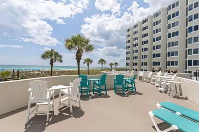 a row of chairs and tables on a balcony with the beach at Top of the Gulf 120 - Shore-side Bungalow Sleeps 4 in Panama City Beach
