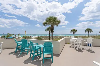 a patio with chairs and tables and the beach at Top of the Gulf 120 - Shore-side Bungalow Sleeps 4 in Panama City Beach