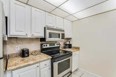 a kitchen with white cabinets and a stove and microwave at Moondrifter 305 - 2 BR - Oceanfront condo Sleeps 6 in Panama City Beach