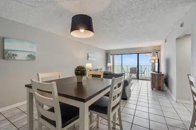 a dining room and living room with a table and chairs at Moondrifter 604 - Emerald Gulf Retreat - Sleeps 6 in Panama City Beach