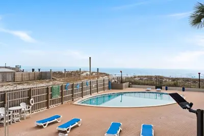 a swimming pool with lounge chairs and the ocean at Moondrifter 205 - Sand-Side Oasis - Sleeps 6 in Panama City Beach