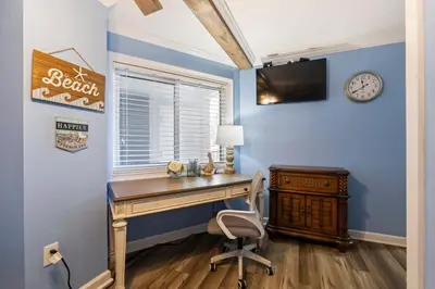 a home office with a wooden desk and a clock at Moondrifter 205 - Sand-Side Oasis - Sleeps 6 in Panama City Beach
