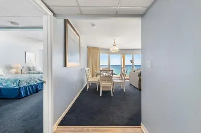 a room with a table and chairs and a bedroom at Long Beach Tower 2 #703 Beachfront 2 BR 2 BA in Panama City Beach