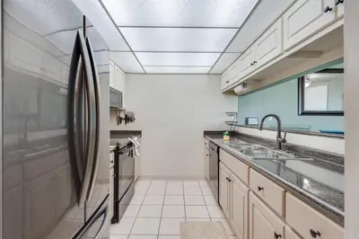 a kitchen with white cabinets and a sink at Sand-Crest Overlook - Moondrifter 201 in Panama City Beach