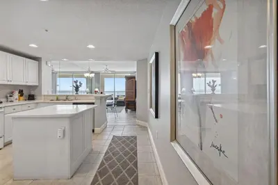 a kitchen with white cabinets and a large painting on the wall at Majestic Condo- Tower 2 #206 3 BR 3 BA Low floor! in Panama City Beach