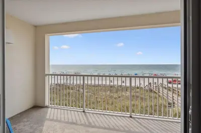 a room with a balcony with a view of the beach at Majestic Condo- Tower 2 #206 3 BR 3 BA Low floor! in Panama City Beach